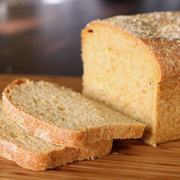 A loaf of anadama bread resting on a wooden cutting board, showcasing its rustic texture and golden-brown crust