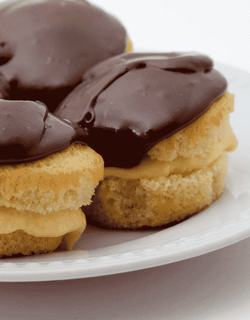 A plate featuring three Boston Cream Pies, each adorned with rich chocolate frosting